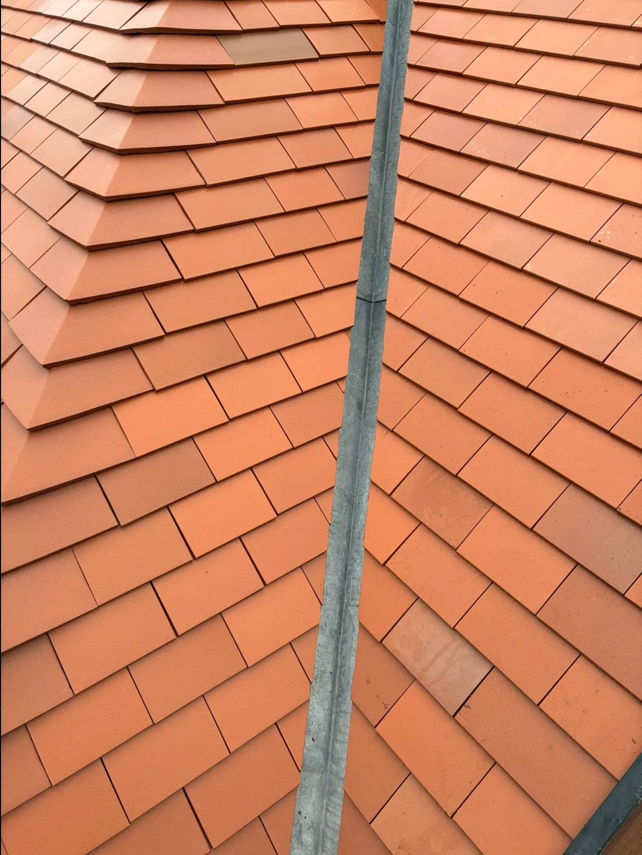 A valley between two newly laid plain clay-tiled roof slopes